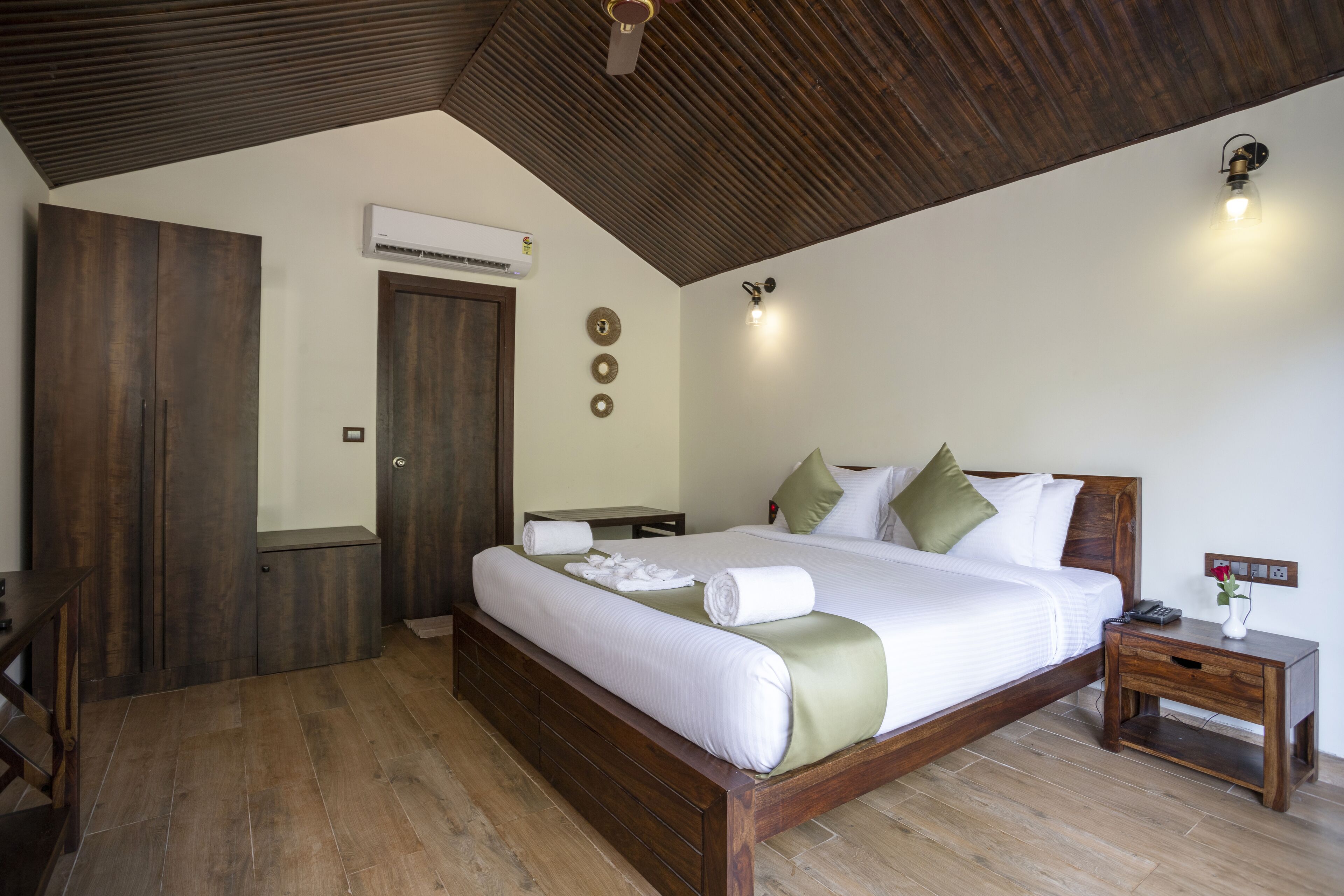 Une chambre spacieuse avec un grand lit, une tête de lit en bois et un plafond en bois.