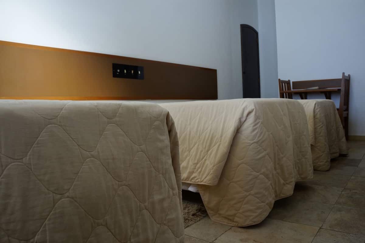 Hotellihuone, jossa on sänky, yöpöytä ja tuoli.