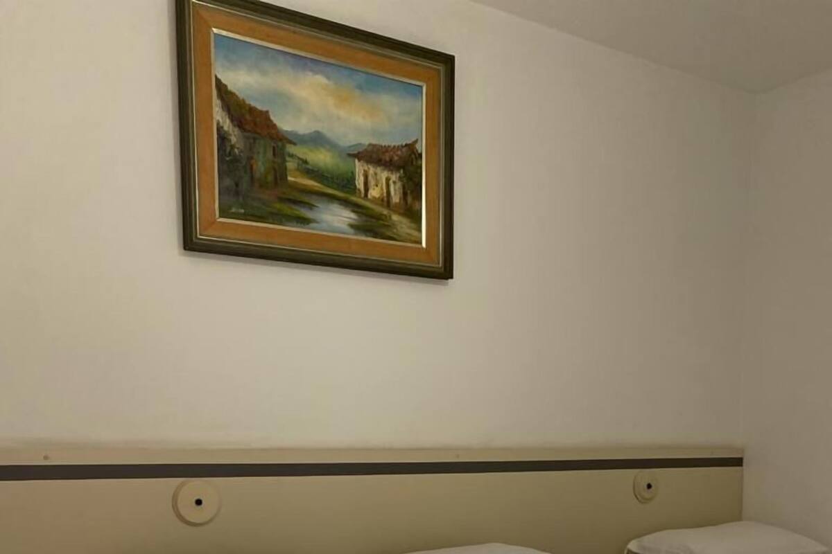 Hotellihuone, jossa on suuri sänky, yöpöytä ja taulu seinällä.