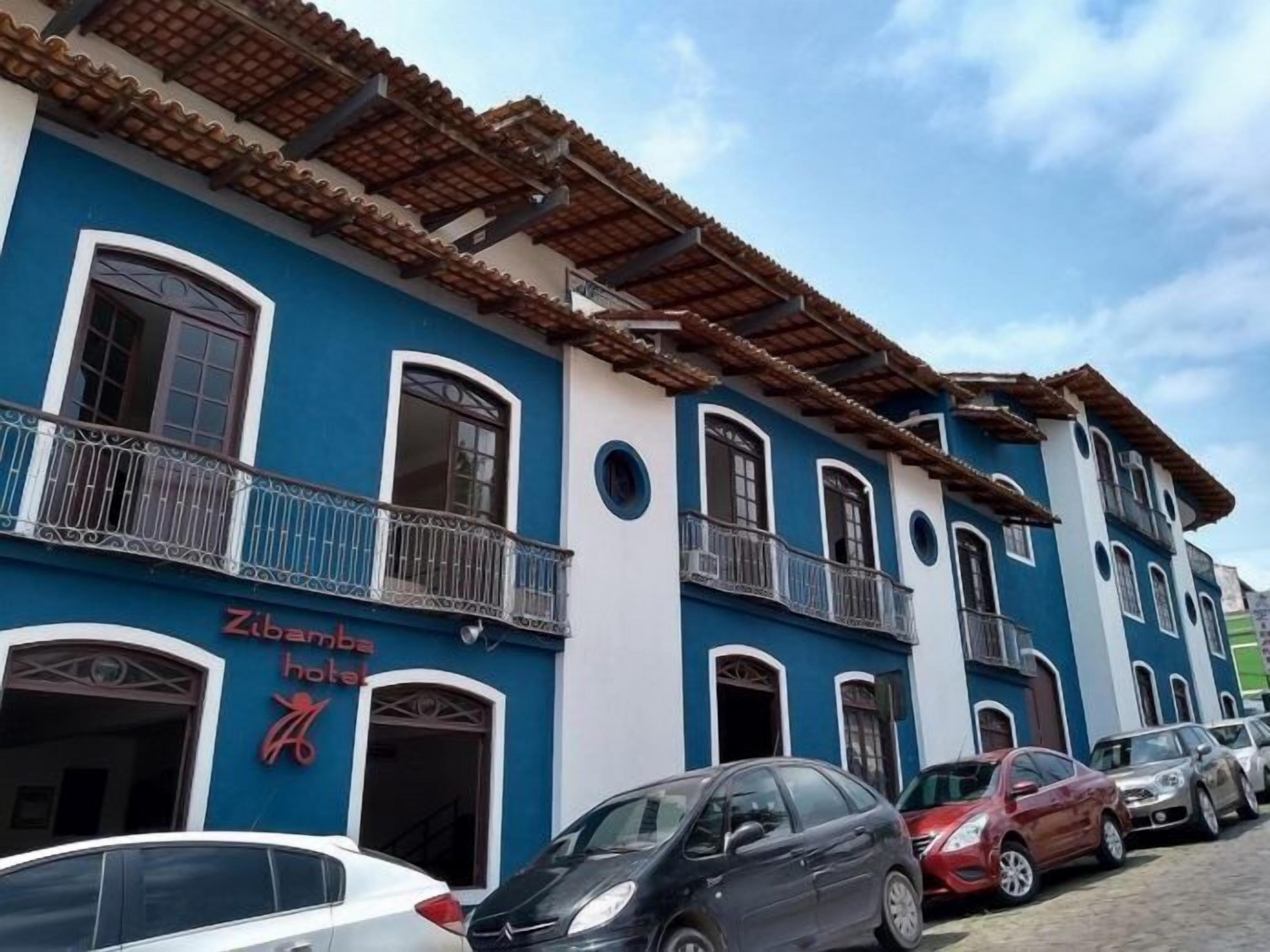 Un hotel con fachada azul, varios balcones y tejado de tejas.