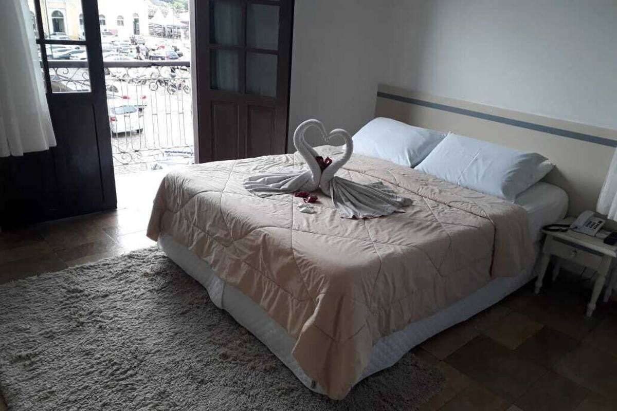 Hotellihuone, jossa on sänky, yöpöytä ja ovi, josta avautuu näkymä kadulle.