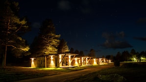 A series of cabins with open porches, surrounded by trees, and illuminated by artificial lighting. - Nordic Lapland Resort (Kalix)