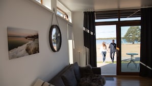 A modern living room with a large window, a sofa, and a painting of a landscape. - Nordic Lapland Resort (Kalix)