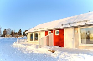 A row of cabins with a red exterior and white trim, surrounded by snow. - Nordic Lapland Resort (Kalix)