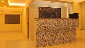 A reception desk with a marble top and a patterned counter, a sign indicating check-in times, and a door leading to another room. - Hotel Niladrii Galaxy (Siliguri)