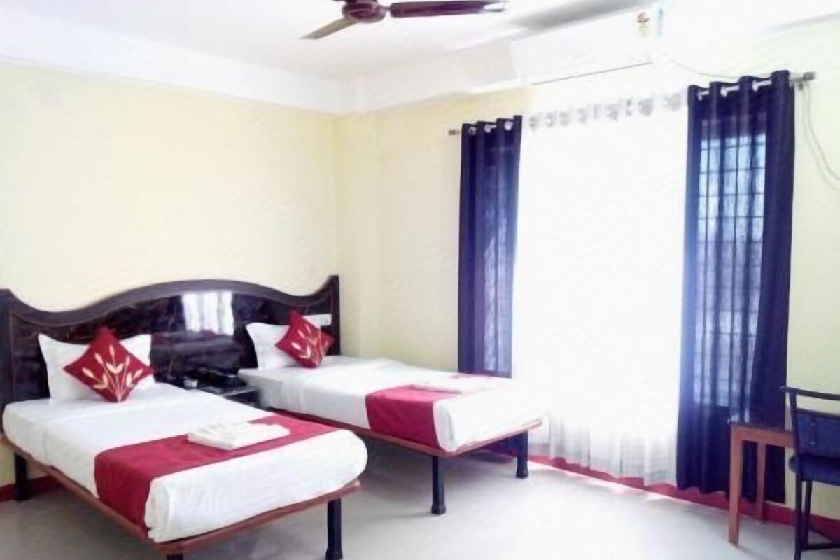 Una habitación con dos camas, un ventilador de techo y una ventana con cortinas.