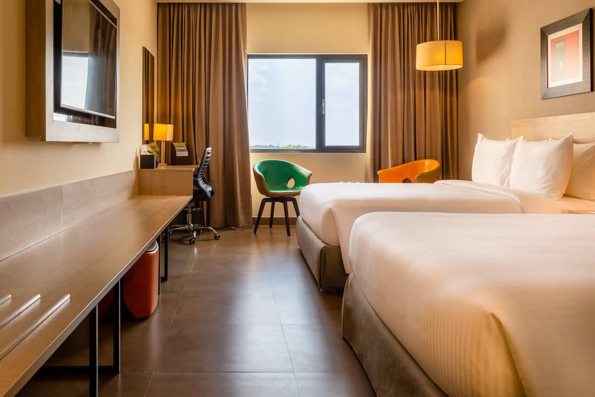Une chambre d’hôtel avec un lit, un bureau, une chaise et un téléviseur.