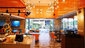 Un restaurante moderno con paredes anaranjadas, sillas negras y anaranjadas, y una mesa de comedor central.