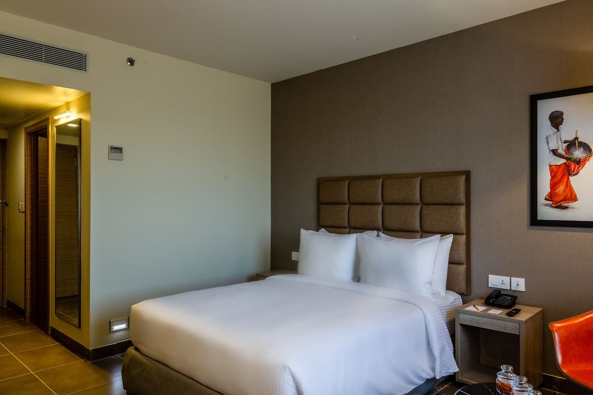 Une chambre d’hôtel avec un grand lit, une table de chevet avec un téléphone et une chaise.