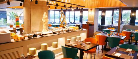Un restaurant moderne doté d’un espace buffet, de nombreuses tables et chaises, et de grandes fenêtres offrant une vue sur l’extérieur.