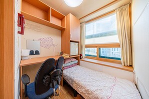 A small bedroom with a single bed, a desk with a chair, a window with curtains, and a wooden shelf. - Dream Single House (Seoul)