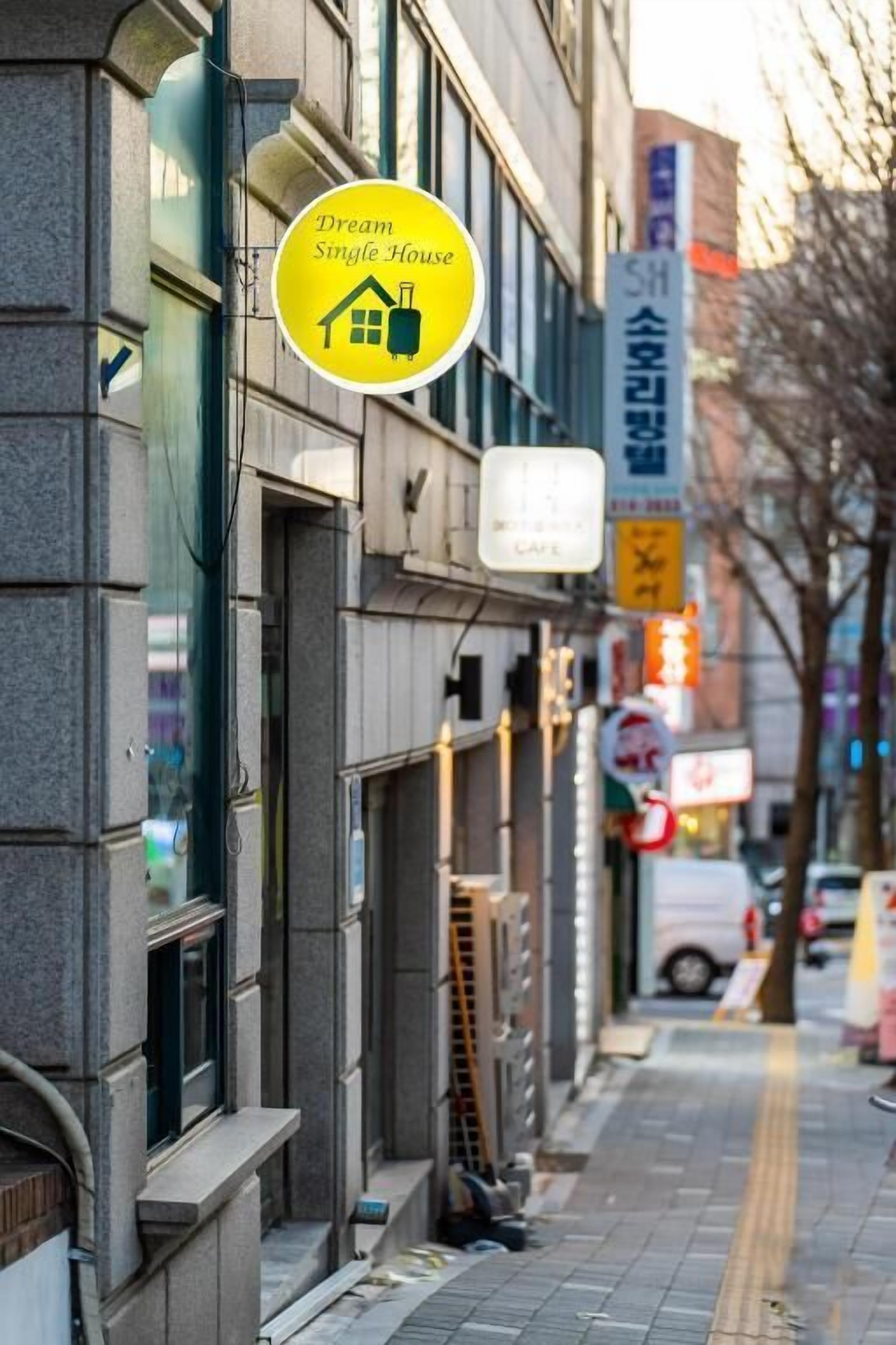 Une vue de rue avec un panneau jaune indiquant qu’une maison est à louer.