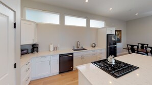 A modern kitchen with white cabinetry, a built-in dishwasher, a stove, and a refrigerator.