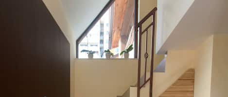 Un escalier avec des marches en bois et une rampe en métal, menant à l’étage supérieur.