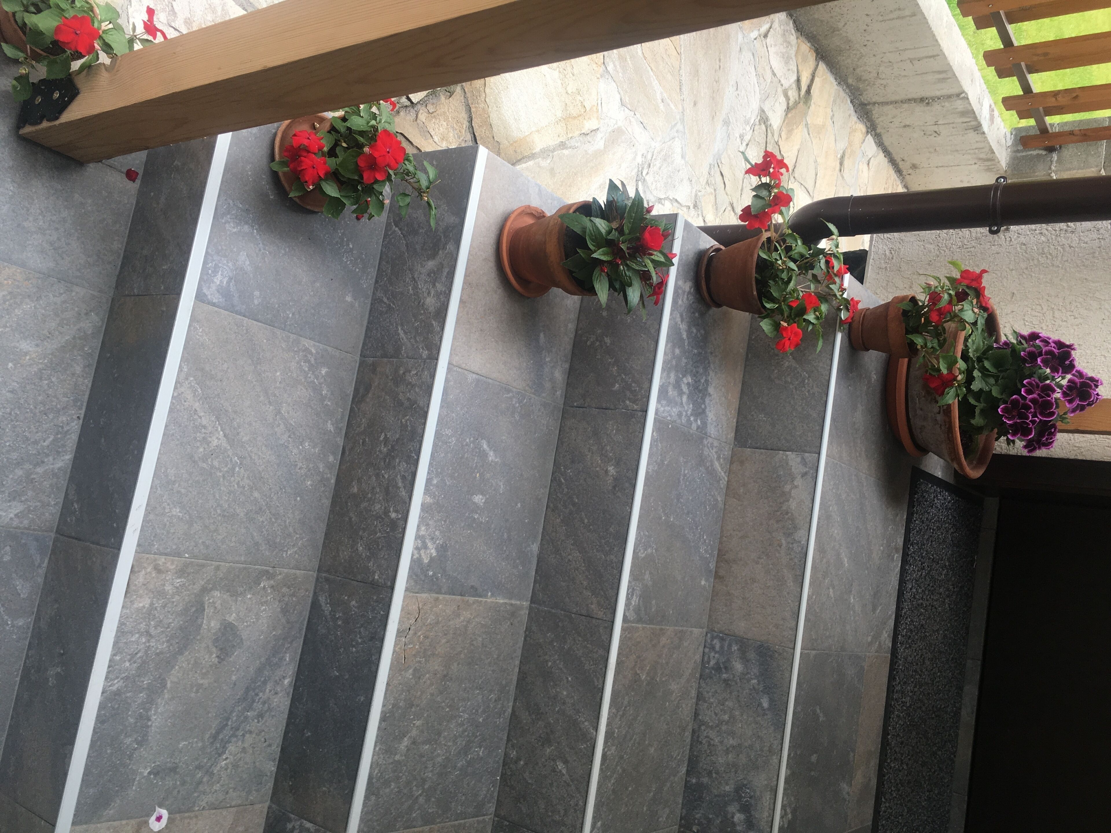 Een betegelde vloer met plantenpotten en een houten balkenconstructie.