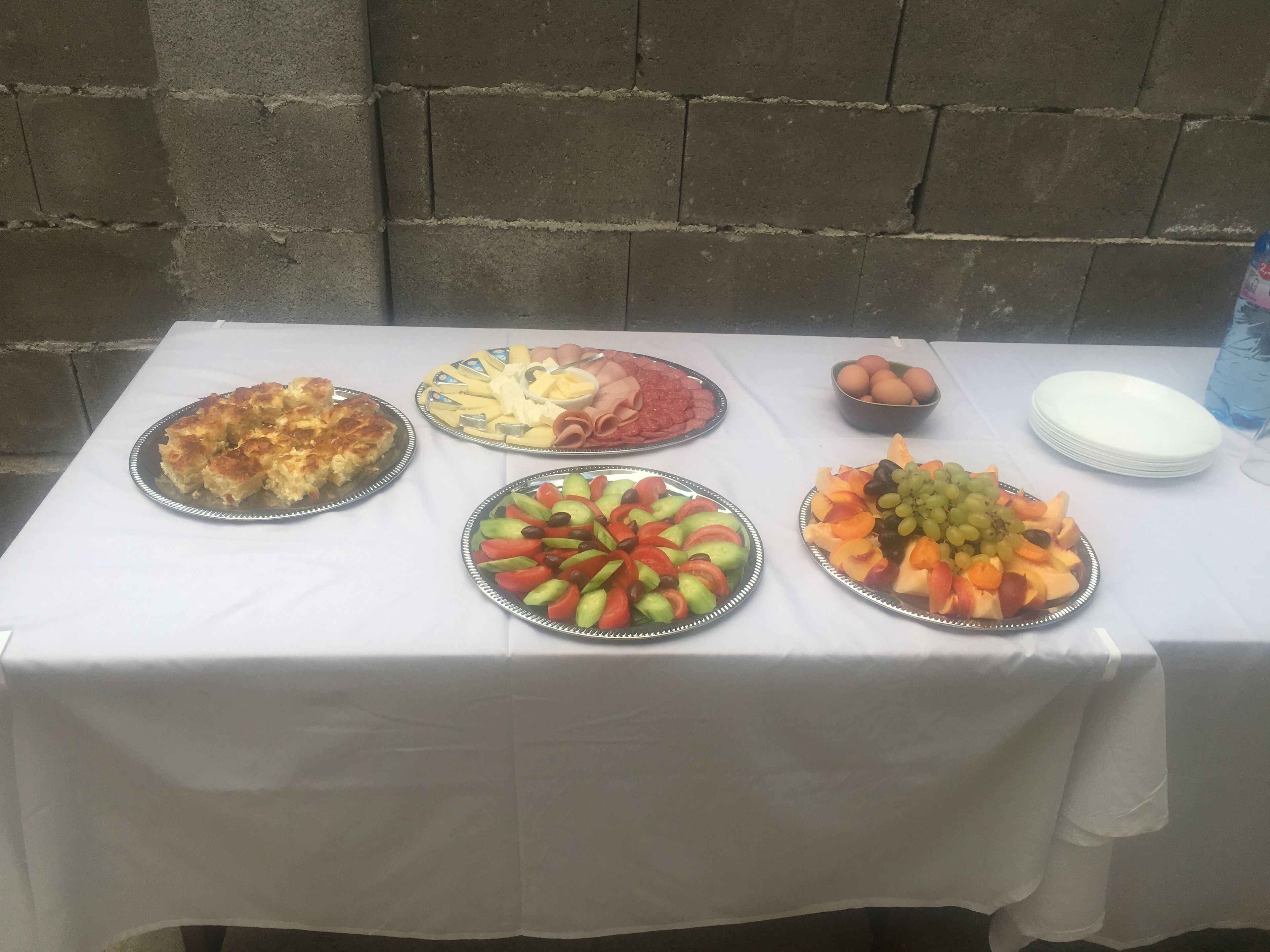 Una mesa con diversos alimentos, incluyendo tarta, queso, jamón, huevos y fruta.