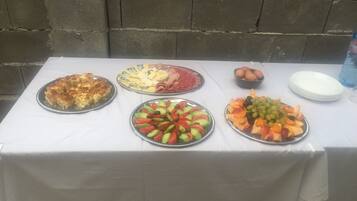 Una mesa con diversos alimentos, incluyendo tarta, queso, jamón, huevos y fruta.