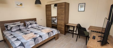 Una camera da letto con un letto, una scrivania, una sedia e un televisore.