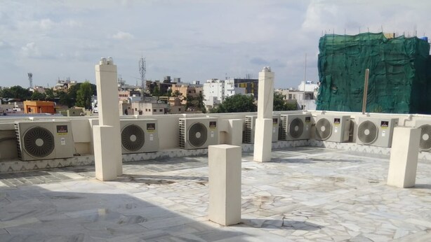 Una terraza en la azotea con varias unidades de aire acondicionado y suelo de baldosas.