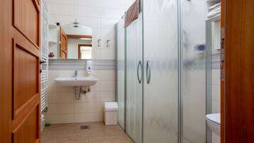 A bathroom with a sink, mirror, and a glass shower enclosure.