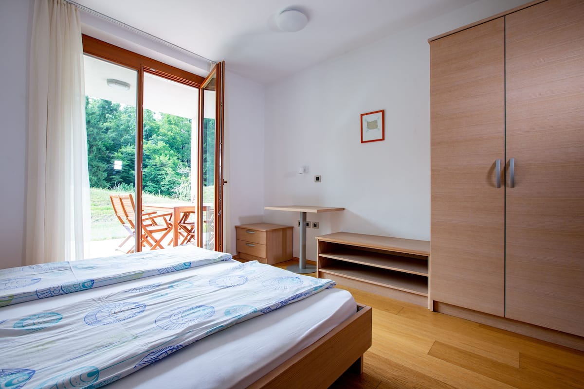 A bedroom with a bed, a desk, and a wardrobe.
