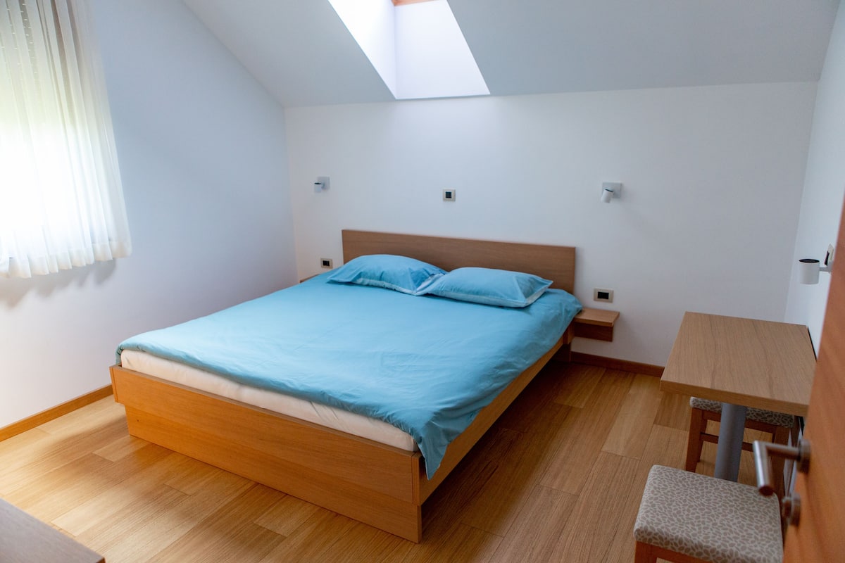 A bedroom with a wooden bed, a small wooden table, and a chair.
