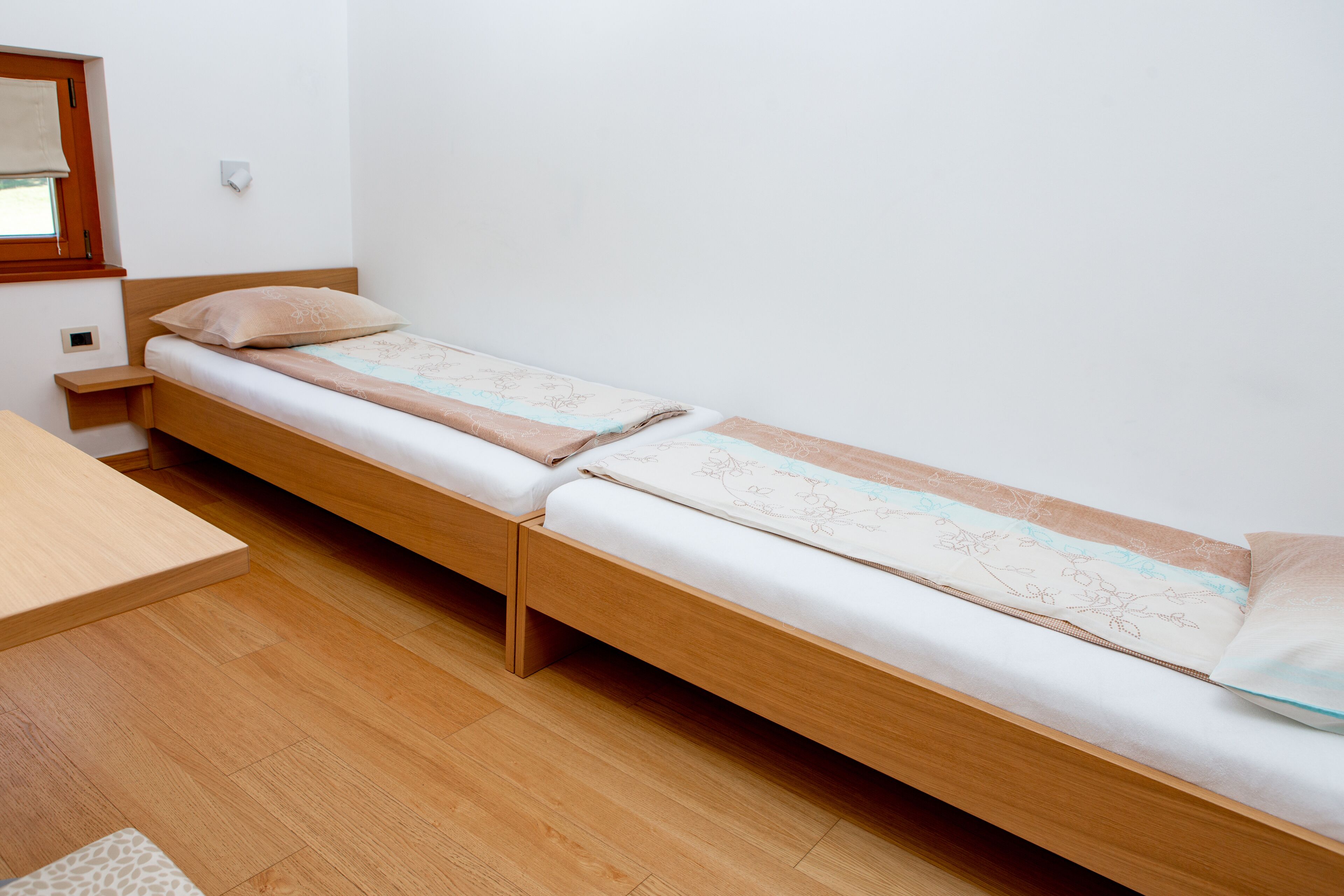 Un lit simple avec un cadre en bois, une table de chevet et une petite étagère.