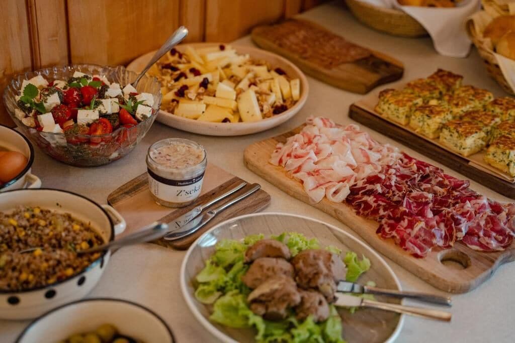 Un tavolo imbandito con diversi piatti, tra cui un'insalata, un tagliere di formaggi e un piatto di carne.