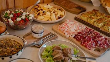 Una mesa con diversos platos, entre ellos una ensalada, una tabla de quesos y un guiso de carne.