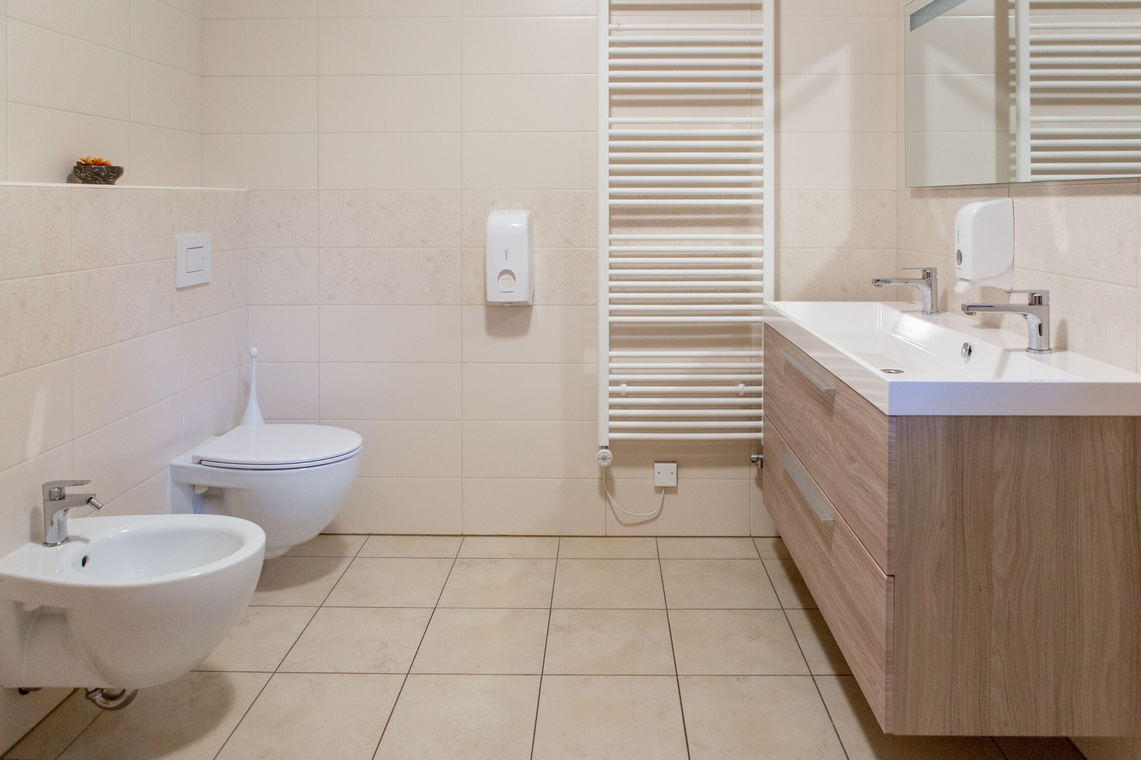A modern bathroom with a bidet, toilet, and a sink with a mirror above.