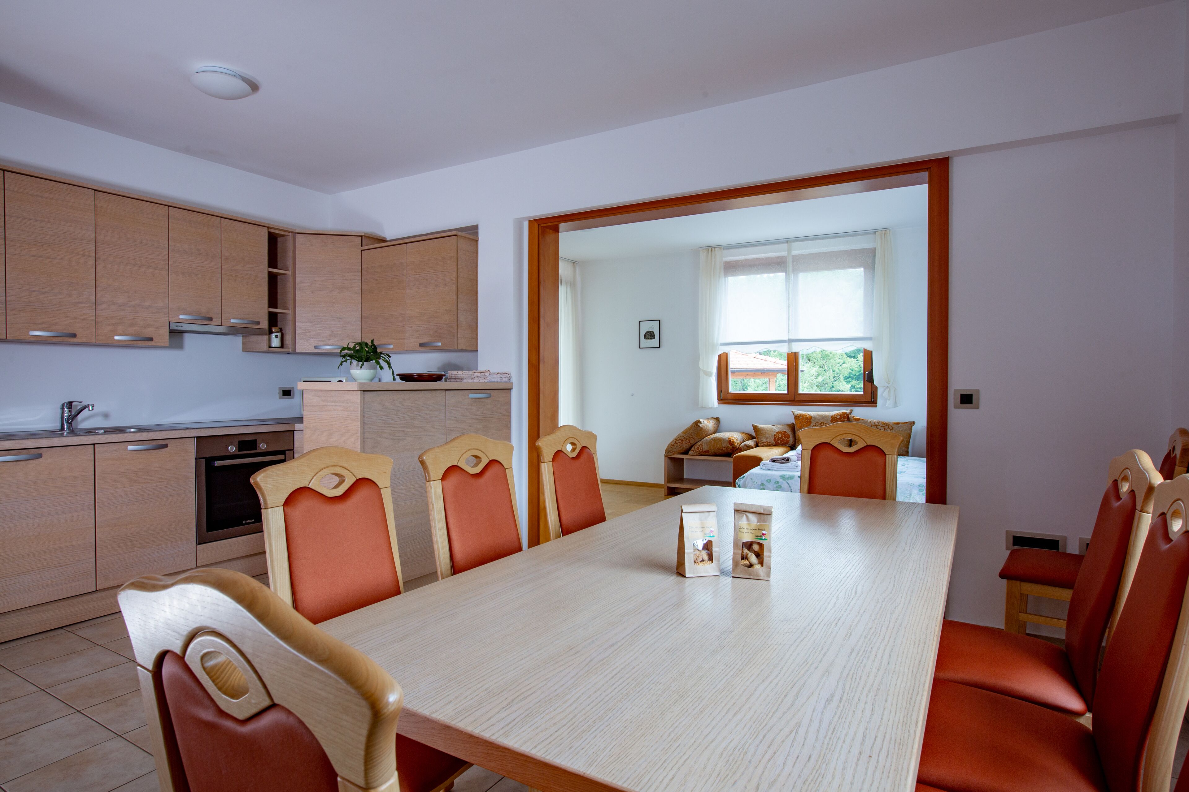 Una cocina moderna con armarios de madera y un comedor con una mesa grande y sillas color naranja.