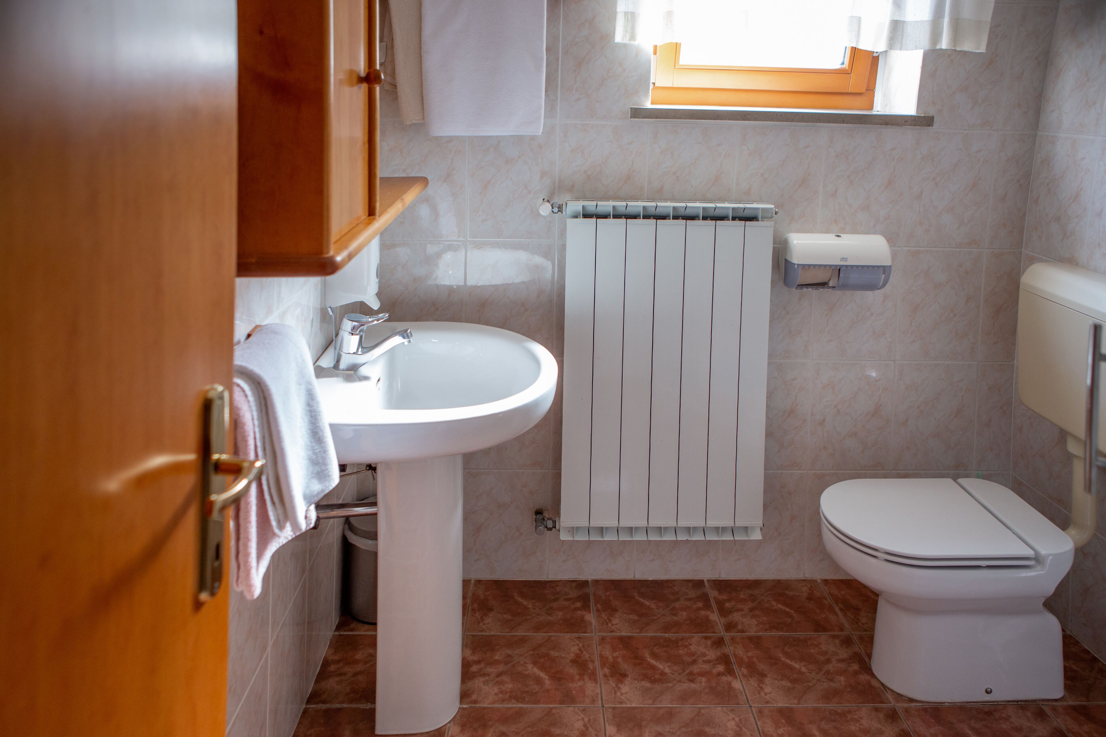 A bathroom with a white sink, toilet, and a towel rack.