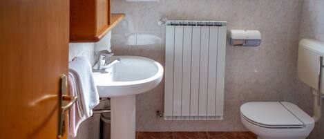 A bathroom with a white sink, toilet, and a towel rack.
