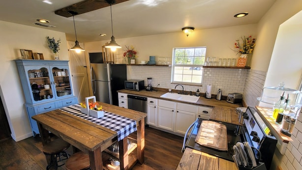 Una cocina moderna con armarios de madera, una isla central y una zona de comedor con taburetes.