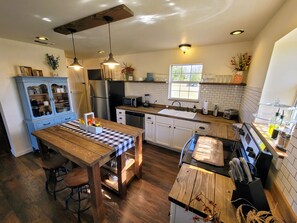 Een moderne keuken met houten kastjes, een centraal eiland en een eethoek met krukken.