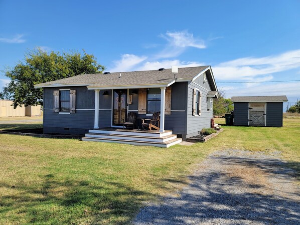 A small house with a porch, a garage, and a well-maintained lawn.