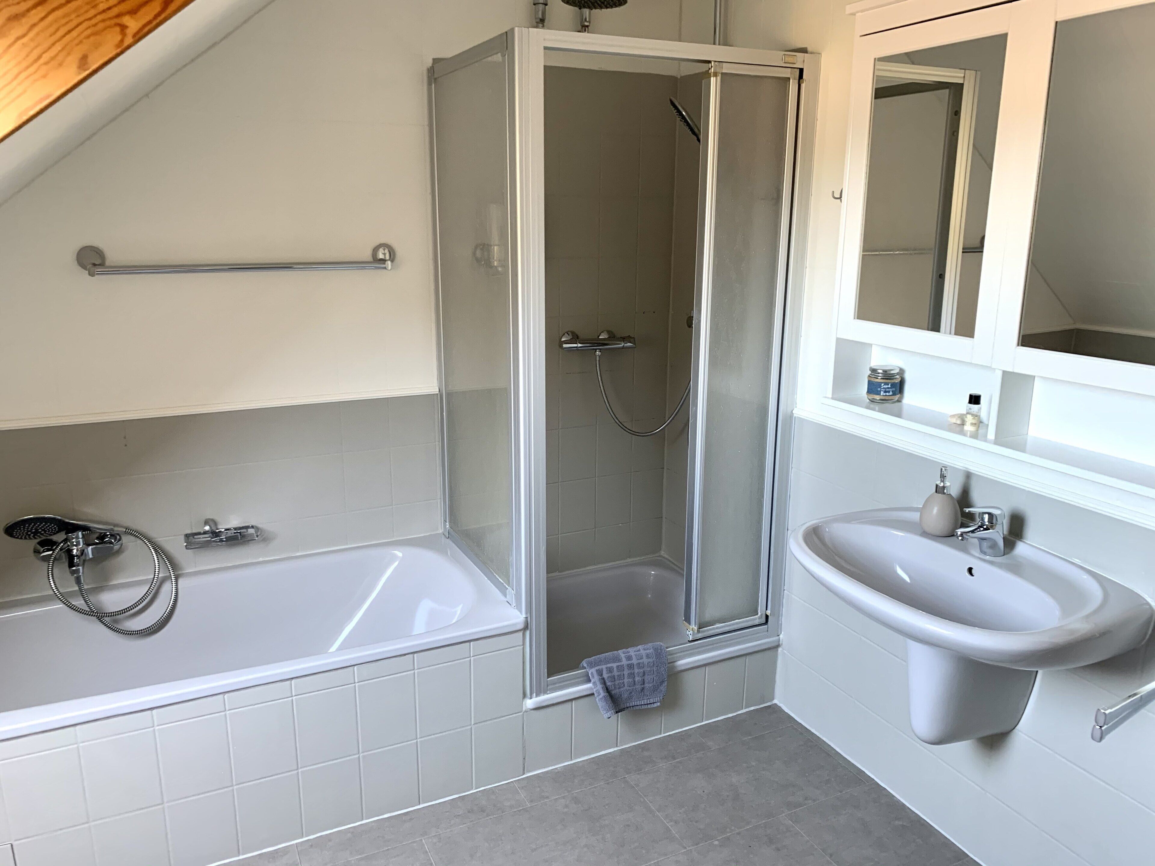 A modern bathroom with a glass-enclosed shower, a bathtub, and a sink.
