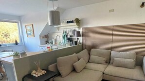 A modern living room with a sofa, a small table, and a kitchen area in the background. - Apartment Seeweg - your time out in the north (Beverstedt)