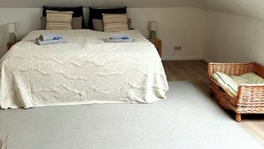 A bedroom with a large bed, a wicker chair, a skylight, and a ceiling lamp. - Apartment Seeweg - your time out in the north (Beverstedt)