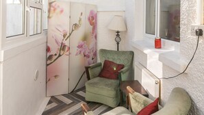 Une pièce chaleureuse avec un fauteuil vert, une chaise assortie, une table en bois et un panneau décoratif orné de motifs floraux.