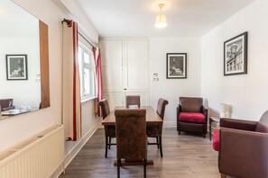 A dining area with a wooden table and chairs, a radiator, and a window with curtains. - 3 Bed Quaint House Town Center (Wexford)