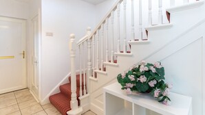 Un escalier avec des rampes blanches et une plate-forme recouverte d’une moquette rouge.