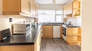 Une cuisine moderne avec des meubles en bois, un plan de travail noir, un four encastré et un lave-vaisselle.