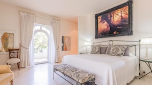 Une chambre à coucher avec un grand lit, un banc, un bureau et un tableau accroché au mur.