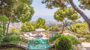 Un espace piscine avec des chaises longues et une vue sur la ville en arrière-plan.