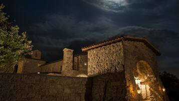 A stone building with a moonlit sky, featuring a prominent archway and a small tower.