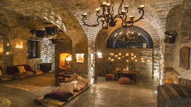 A cozy, stone-walled room with a fireplace, a chandelier, and a comfortable seating area. - Eremito (Parrano)