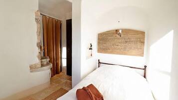 A bedroom with a bed, a stone staircase, and a wall-mounted plaque.