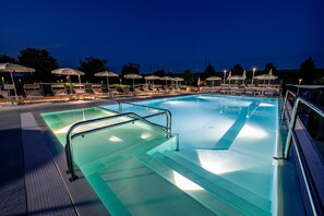 A swimming pool with lounge chairs and umbrellas, surrounded by a fence. - Hotel Fracanzana (Montebello Vicentino)