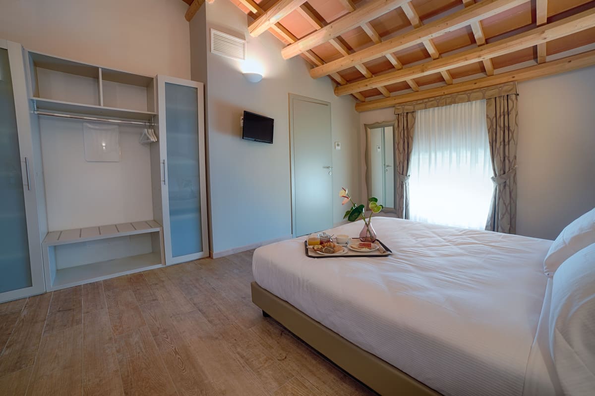 Een slaapkamer met een bed, een dienblad met ontbijtartikelen, een garderobe en een televisie.